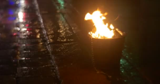 Tűz az égő, egy vödör színes lámpafény tükrözi a szabadban út kikövezve kövek tűz eloltására fáklyák van égető narancs láng éjszaka — Stock videók
