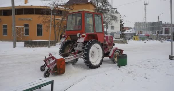 人们在巷子里长凳红色拖拉机推土机正在打扫公园小巷中移除雪中央公园的 Konotop 光秃枝树建筑 — 图库视频影像