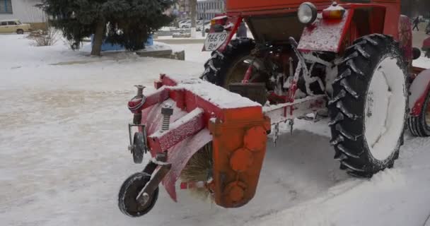 Borsten är roterande i röd traktor Scoor rengöring en skopa Bulldozer är städning en Park Alley tar bort snö Central Park Konotop kala grenar träd — Stockvideo