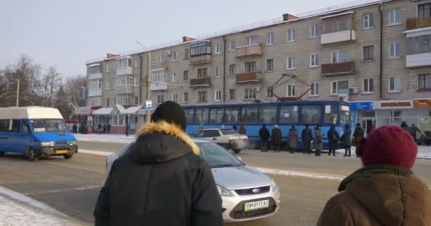 Velho eléctrico na Avenida Mir em Konotop City Ucrânia Inverno Blue Tram chega Pessoas estão andando rápido para tomar um eléctrico Carros estão passando entre as pessoas e um vagão — Vídeo de Stock