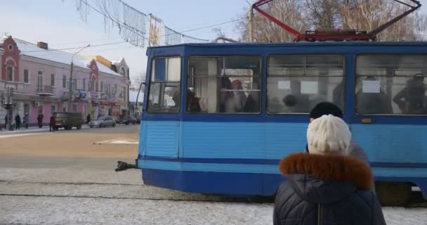Tram bleu part à Mir Avenue à Konotop City Ukraine hiver Noël femmes vieilles dames sont debout à la gare de tramway parler magasins à la gare — Video