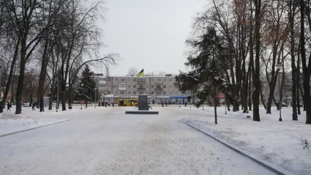 우크라이나 국기 전 레닌의 기념 받침대 도시 풍경 사람들이 코노톱 시 우크라이나의 행정 건물에서 겨울 공원에서 걷고있다 — 비디오