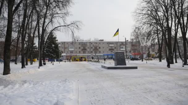 Drapeau ukrainien agite placé sur le piédestal Les gens du piédestal commémoratif de Lénine marchent près du parc Wintery au bâtiment administratif de Konotop — Video