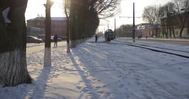 Ludzie czekają na tramwaj Weź tramwaj ludzie wejdziesz do Old Green tramwaj samochody są jazdy na Mir Avenue Snow na ziemi na Ukrainie Konotop City — Wideo stockowe
