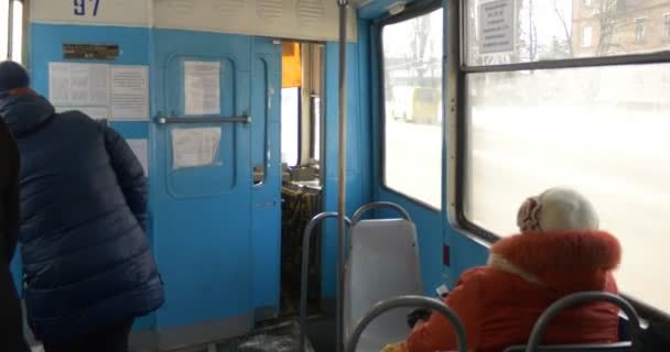 As pessoas estão sentadas dentro do velho carro elétrico azul Backs View of The Tram Driver 's Cab View of The Street From The Tram' s Window Frost and Snow in Konotop City — Vídeo de Stock