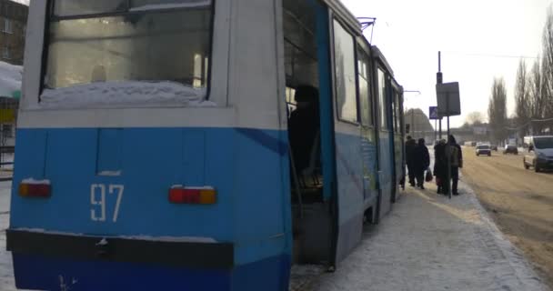 Tramstation op Mir Avenue in Konotop stad mensen betreden en zit in oude wagon van tram tramstation Auto's rijden langs de straat kerstavond — Stockvideo