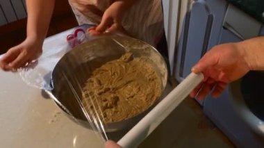 El ile hamur Polietilen Film koca bir kase kapsayan ve karısı mutfak at yapıyoruz bir hamur bir bisküvi kek için masada yemek