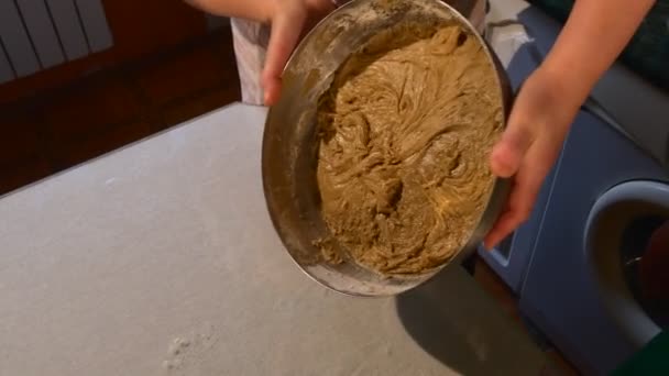 Las manos femeninas sostienen un tazón de masa mostrando su estructura gruesa Las personas en la cocina están haciendo una masa para un pastel de galletas Cocinando en la mesa — Vídeos de Stock