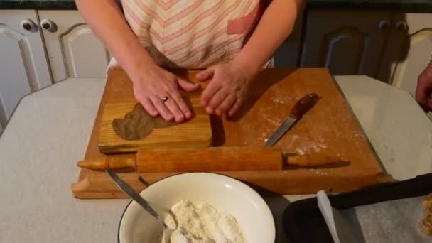 Frau gibt Teig in eine bockförmige Form und holt ihn mit dem Messer heraus Ehemann und Frau Familie backen Kekse in Holzform in ihrer Küche — Stockvideo