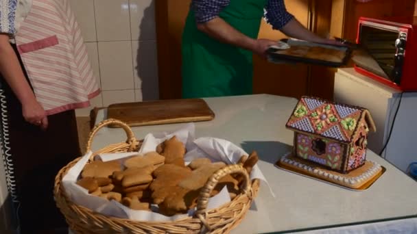 Homem tirando a bandeja de cozimento com biscoitos da família do forno está cozinhando um bolinho em forma de homem e mulher bolos decorados com mastique biscoitos na cesta — Vídeo de Stock