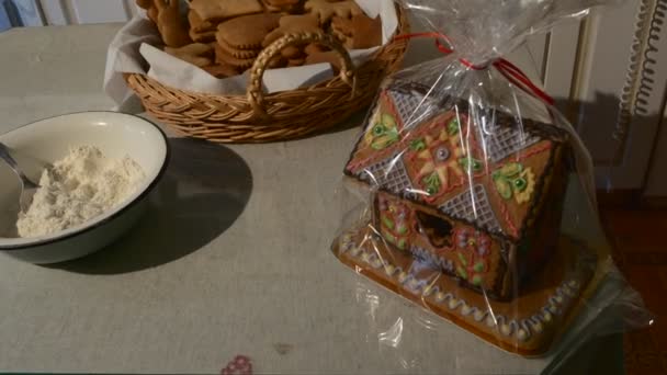 Haus-Kuchen verpackt in Polyethylen-Folie herzförmige Kekse in einem Korb Haus-förmigen Kuchen mit Mastique Schüssel aus Mehl verziert hausgemachte Weihnachtsgeschenke — Stockvideo