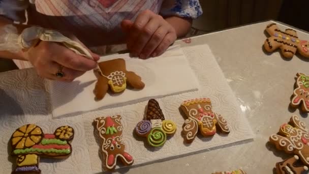 As mãos estão pintando com mastique branca Angel-Cookie Woman está decorando um biscoitos de biscoitos de Natal decorados com mastique colorido em uma mesa — Vídeo de Stock