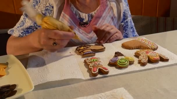 Mulher está pintando um biscoito com mastique amarelo Mulher está decorando um biscoitos de biscoitos de Natal decorados com mastique colorido em uma mesa de chocolate — Vídeo de Stock