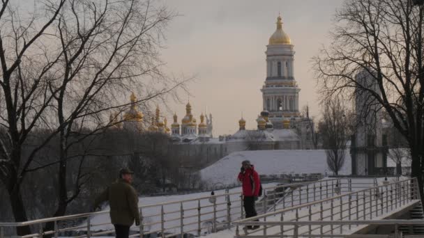 Man mötte sin vän vifta med sin Hand mannen i röd talar via telefon vifta med sin Hand två män närma varandra och ge en kram Kievo-Pecherskaya Lavra — Stockvideo