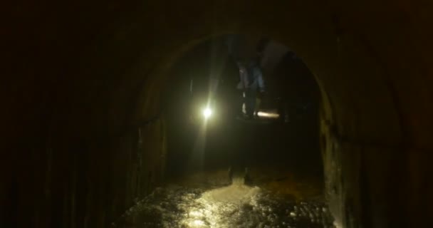 Man Lights The Water Stream Semicircular Ceiling of a Cave Tourists in a Dark Cave at The New Year's Excursion to Kiev Underground People Light the Way — Stock Video