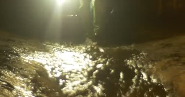 Water stream kleine waterval close-up mensen benaderden toeristen in een donkere grot op de Nieuwjaars excursie naar Kiev Underground mensen licht de weg — Stockvideo
