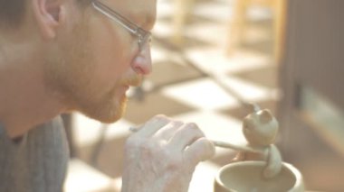 Man Bir Kil Pot ve Kedi Heykelciliği Su Ham Kil Özenle Gözlük bir Fırça Orta Yaşlı Man Kullanarak Çalışma ile Bir Pot Cover Sabit Kaplama