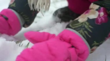Kar kış binalar kar buz gibi kız çiçekli ceket ve pembe pantolon oynayan bir yerden kar yığını pembe eldiven çocukça elinde tut