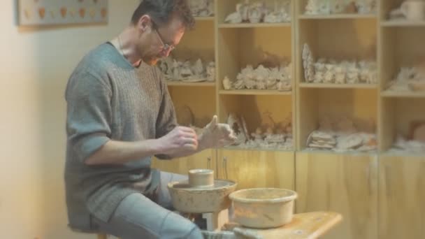 Člověk se musí otáčet keramiky kolo dychtivě formovat Clay Pot pozorně člověk je, brýle se dívá na pracující Pot keramiky kolo Workshop regálech