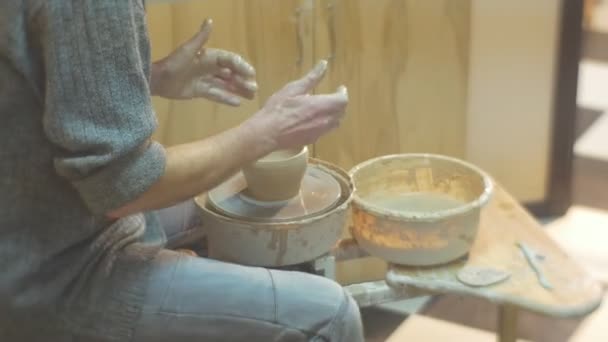 Man roterar en Pottery Wheel Molding en lera potten uppmärksamt med spatel titta noga på potten arbetar på en Pottery Wheel keramik Verkstad — Stockvideo