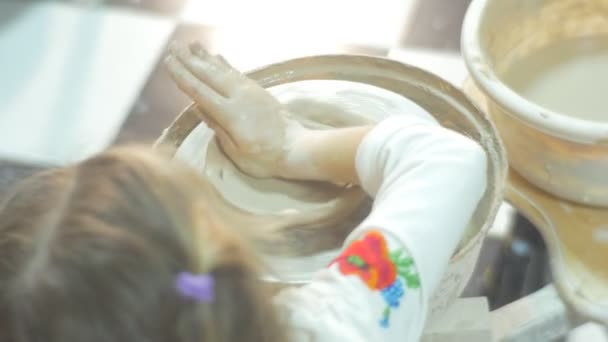 아이가 꽃병 탑 다운 작은 금발 소녀가 도자기 작업장에서 집중적으로 선물을 만드는 도자기 바퀴에 노력하고 조각 클레이 서클을 누르고있다 — 비디오