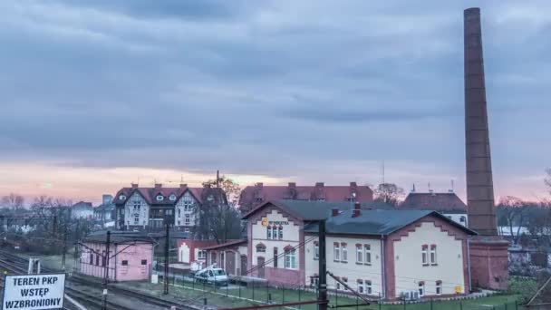 Huizen gebouwen op de spoorweg trein is bewegende Hyperlapse Titelapse industrie hoge buis zonder rookwolken op een hemel avond komt wordt donkerder bomen — Stockvideo