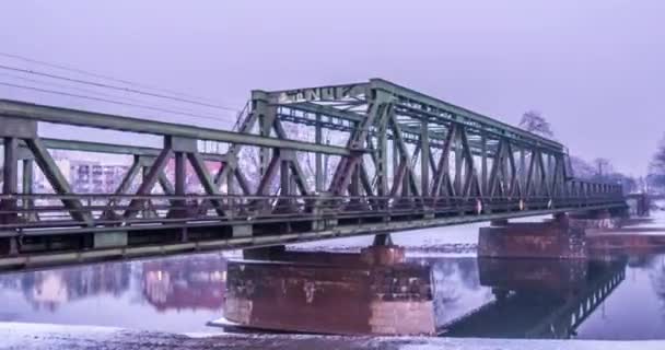 Züge fahren durch eine Eisenbahnbrücke mit Metallkonstruktion darauf Hyperlapse Zeitraffer Eisenbahnbrücke durch Fluss Dämmerung Schneehorizont Winterlandschaft — Stockvideo