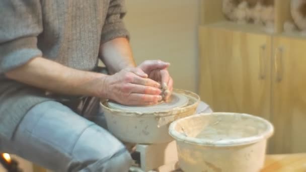 Чоловік середнього віку обертає гончарне колесо швидко натискаючи глину зі своїм обличчям Концентрований чоловік намагається важко навчитися гончарному ремеслу в майстерні — стокове відео