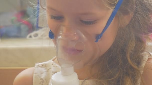 Menina está olhando para baixo Playig leitura sentado máscara de nebulizador em seu rosto segurando um telefone móvel Kid está respirando através de vapor inalador está levantando — Vídeo de Stock