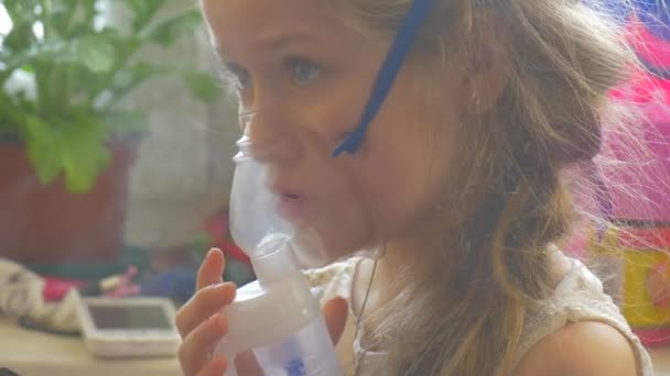 Kind berührt die Maske und spielt weiter mit Handy mit Vernebelungsmaske im Gesicht, in der Hand ein Handy, das Kind atmet durch Inhalator — Stockvideo