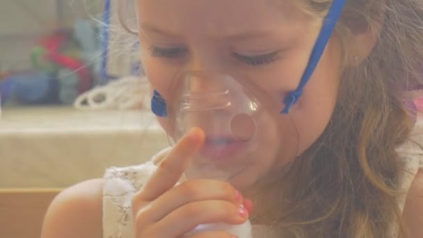 Dziecko jest prostowanie jej maska patrząc w dół twarzy bliska dziewczyna siedzi z nebulizatora maska ustalona na jej twarzy oddychanie parą wodną przez inhalator — Wideo stockowe