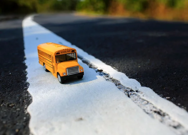 Modello di giocattolo giallo scuolabus su strada di campagna — Foto Stock