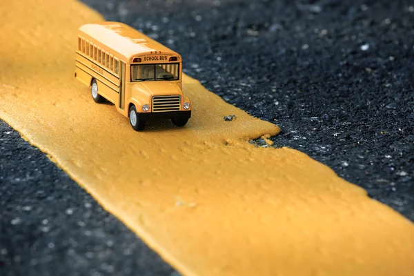 Modello di giocattolo giallo per scuolabus sulla linea gialla della strada di campagna . — Foto Stock