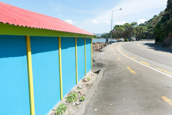 Estrada costeira passado colorido azul e amarelo barco-galpão com ro vermelho — Fotografia de Stock