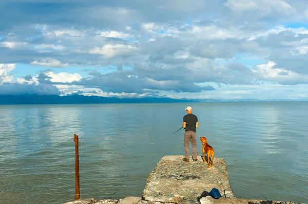 Geduld door man en hond staande op oude pier op Firth van T — Stockfoto