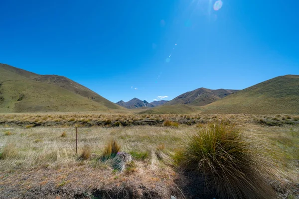 山頂上空のレンズフレアとリンディス峠の谷を覆うタソックス 有名なロードトリップ中央オタゴニュージーランド — ストック写真