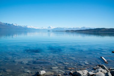 Sahil şeridi ve manzarası sakin Pukaki Gölü 'nü aşçı dağı ve güney Alpleri mesafesinde.