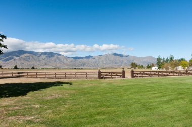 Uzak dağlarla yeşil arazide çit ve çit var..