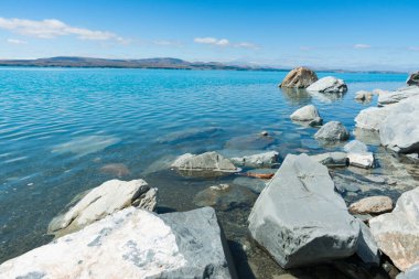 Gri taşlı göl kenarı ve turkuaz mavi kar suyu Güney Ilsand Yeni Zelanda 'daki Pukaiki Gölü manzarasını besler..