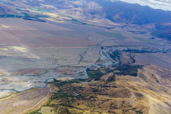 Aerial view of braided river running through Canterbury landscape through perspex canopy from within glider cockpit in flight