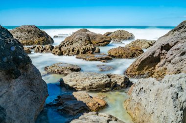 Yeni Zelanda 'daki Maunganui Dağı' nın engebeli kıyılarında dalgalanan beyaz su pürüzsüzleşti..