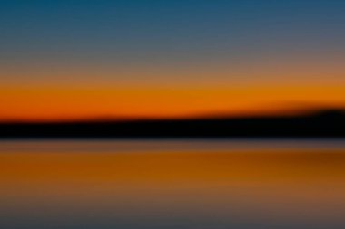 Güneş doğumu koyu üzerinde soyut parlak turuncu renk ufkun üstünde ve altında parlıyor.