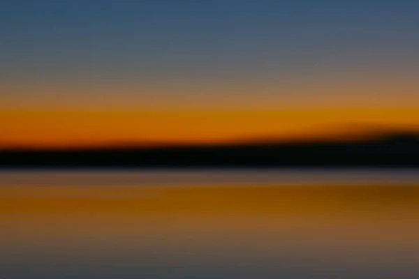 地平線の上と下の明るいオレンジ色の輝きを持つ湾の上の日の出抽象 — ストック写真