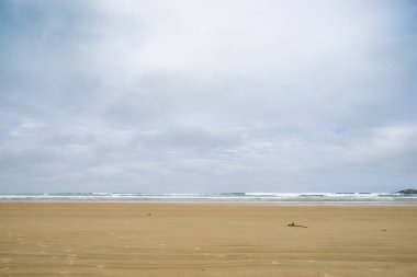 Geniş, düz bir sahil, dalgalar yükselmiş ve alçak dalgalar ufukta Catlins, Yeni Zelanda 'da minimalist stil kıyı görüntüsü kırıyor..