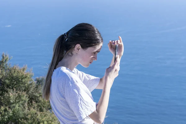 Teenager Top Mount Maunganui Checking Device While Shading Screen Blue — Stock Photo, Image