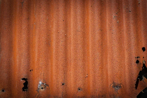 Rusty old corrugated sheet iron junk left on wall to rust away in close-up for background