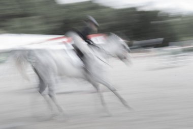Soyut beyaz at ve binici hız ve eylemde bulanıklaştı.