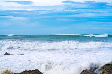 Önünde kayalar olan Maunganui Dağı 'nda dramatik fırtına dalgaları.