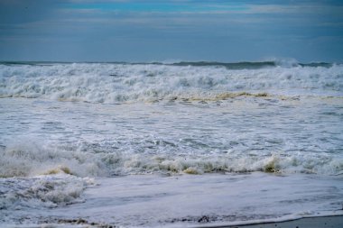 Maunganui Dağı sahilinde dramatik fırtına dalgaları ve beyaz köpük.