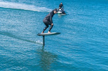 Auckland Yeni Zelanda - 17 Haziran 2021; Auckland limanı Stanley Körfezi 'ndeki jet-ski' nin arkasında çekilen folyo levhası 